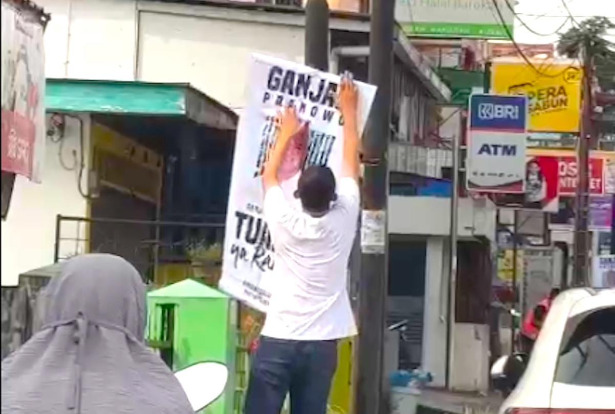 Pihak yang mengaku sebagai petugas Satpol PP mencopoti poster bergambar Ganjar Pranowo yang terpasang di berbagai titik di Kota Pematang Siantar, Sumatera Utara. Foto: tangkapan layar video/Twitter